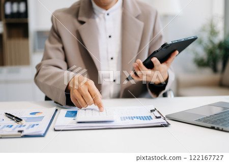 Man counting coins on calculator taking from the piggy bank. hand holding pen working on calculator to calculate on desk 122167727