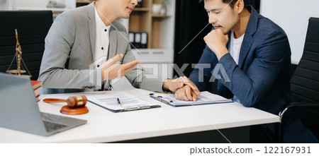 Judge gavel with scales of justice, Business and lawyer or counselor consulting and discussing contract papers with laptop and tablet at law firm 122167931