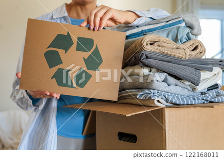 Female hands holding signboard textile clothes recycling reusing zero waste closeup Female hands holding signboard textile clothes recycling reusing zero waste closeup 122168011