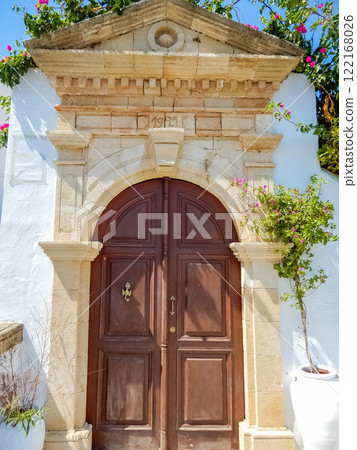 Historic wooden door framed by stone arch and flowers under a Mediterranean sky. High quality photo Historic wooden door framed by stone arch and flowers under a Mediterranean sky. High quality photo 122168026