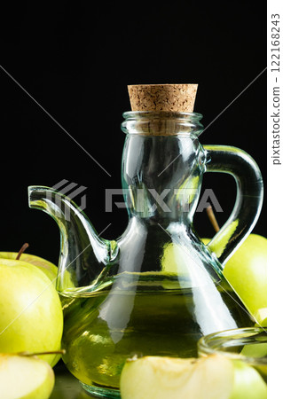 Apple cider vinegar in a glass vinegar bowl among apples Apple cider vinegar in a glass vinegar bowl among apples 122168243