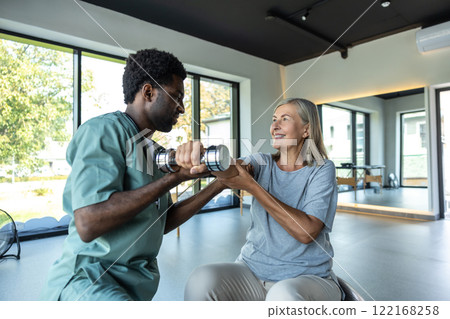 Chiropractor consulting adult patient for recovery after injury through rehabilitation 122168258