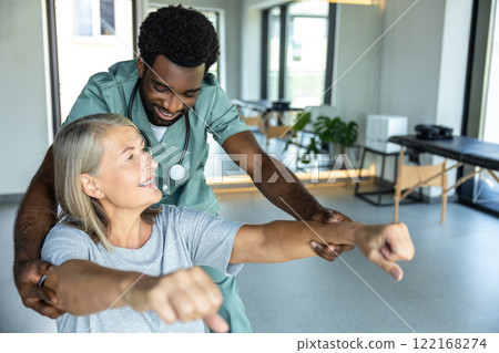 Man chiropractor assisting adult woman patient with pain relief and recovery through rehabilitation 122168274