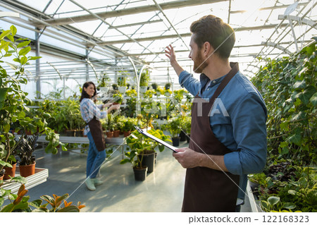 Male supervisor working in a greenhouse and looking positive 122168323