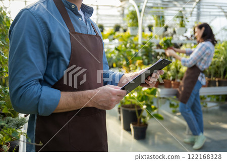 Male supervisor working in a greenhouse and looking positive 122168328
