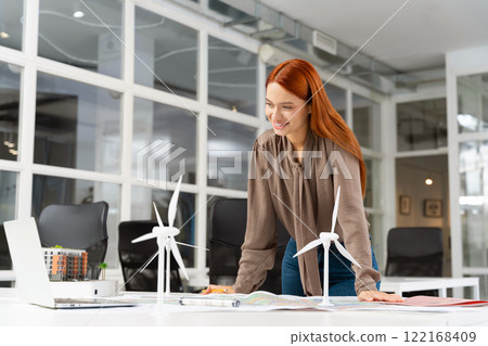 Young female specialist working on a wind turbine project and looking involved Young female specialist working on a wind turbine project and looking involved 122168409