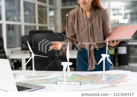 Young female specialist working on a wind turbine project and looking involved Young female specialist working on a wind turbine project and looking involved 122168417