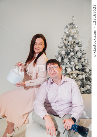 Man and woman in pink clothes with a gift at the Christmas tree. Man and woman in pink clothes with a gift at the Christmas tree. 122169522