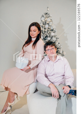 Man and woman in pink clothes with a gift at the Christmas tree.  122169576