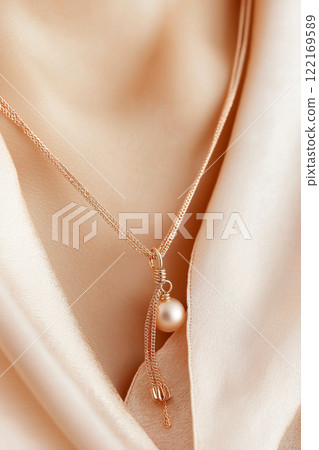 An exquisite golden bead necklace resting elegantly against a soft beige fabric. The design features a series of small, lustrous gold beads strung along a delicate chain, sophistication, simplicity 122169589