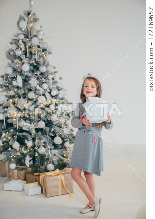 Cute little girl with gift in box and christmas tree 122169657