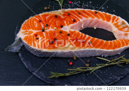 Raw salmon steak with spices on black slate Raw salmon steak with spices on black slate 122170939