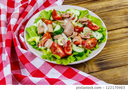 Tasty tuna salad with lettuce and fresh vegetables on wooden table 122170983