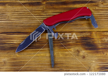 Red all purpose pocket knife on a rustic wooden background. Top view Red all purpose pocket knife on a rustic wooden background. Top view 122171080