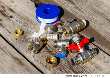 Various plumbing spare parts and sealing tape on rustic wooden background Various plumbing spare parts and sealing tape on rustic wooden background 122171090