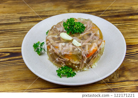 Meat aspic in a plate on a wooden table. Traditional russian dish 122171221