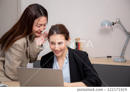 Two business woman gossip while whispering and secret in modern office. 122171929