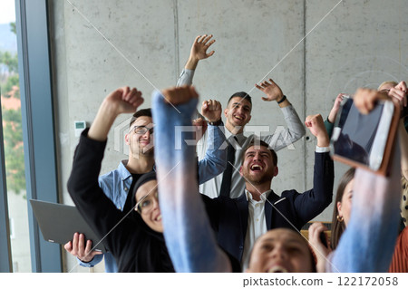 A diverse team of business professionals ecstatically celebrating their success in a modern office, expressing triumph and unity after achieving their goals A diverse team of business professionals ecstatically celebrating their success in a modern office, expressing triumph and unity after achieving their goals 122172058