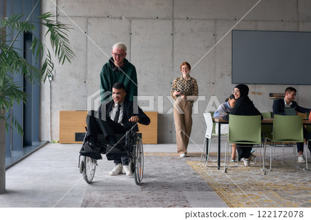 A diverse team of business colleagues, including a director in a wheelchair, engages in a collaborative discussion as they move together through a modern office space A diverse team of business colleagues, including a director in a wheelchair, engages in a collaborative discussion as they move together through a modern office space 122172078