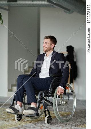 A businessman in a wheelchair enjoys a moment of laughter by a large window in a modern office, embodying positivity, resilience, and a balanced approach to work and life. A businessman in a wheelchair enjoys a moment of laughter by a large window in a modern office, embodying positivity, resilience, and a balanced approach to work and life. 122172151