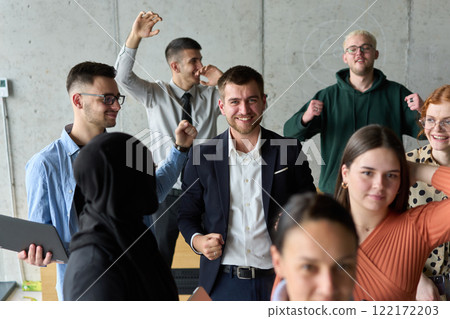 A diverse team of business professionals ecstatically celebrating their success in a modern office, expressing triumph and unity after achieving their goals 122172203