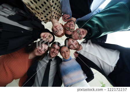 A diverse group of business professionals standing together in a powerful, united pose, captured from a low-angle perspective, exuding confidence and teamwork 122172237