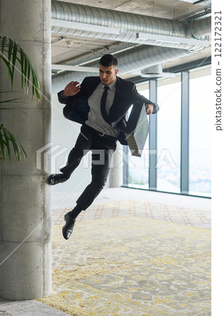 A businessman ecstatically jumping in a modern office, holding a briefcase in his hands, celebrating a moment of success and triumph. A businessman ecstatically jumping in a modern office, holding a briefcase in his hands, celebrating a moment of success and triumph. 122172321