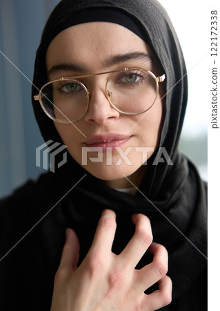 A stunning Muslim businesswoman is captured in a close-up portrait, showcasing her captivating green eyes behind stylish prescription glasses, radiating elegance and confidence A stunning Muslim businesswoman is captured in a close-up portrait, showcasing her captivating green eyes behind stylish prescription glasses, radiating elegance and confidence 122172338