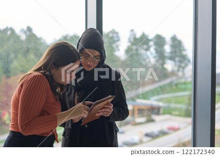 Two colleagues are having a productive conversation while looking at a tablet. Two colleagues are having a productive conversation while looking at a tablet. 122172340