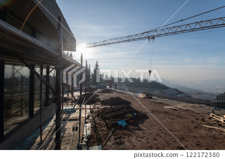 The exterior of a business building under construction is surrounded by trucks, cranes, and various construction materials, creating a bustling scene of an expansive industrial worksite in progress The exterior of a business building under construction is surrounded by trucks, cranes, and various construction materials, creating a bustling scene of an expansive industrial worksite in progress 122172380
