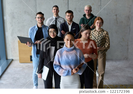 A diverse and determined team of business professionals stands confidently in an office, ready to tackle new business plans and challenges with a focus on success and growth 122172396