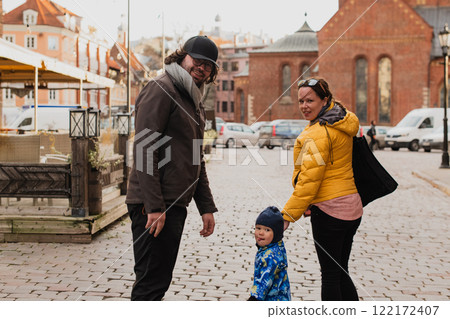 Parents walking hand in hand with their son through the charming city streets, enjoying the warmth of the season and creating joyful memories together 122172407