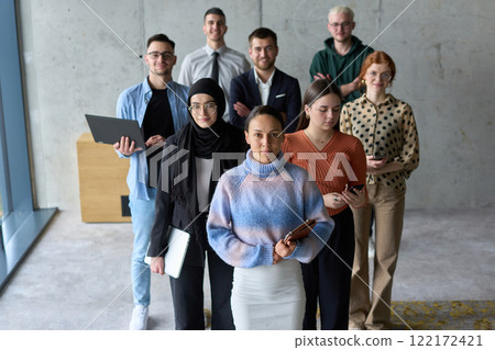 A diverse and determined team of business professionals stands confidently in an office, ready to tackle new business plans and challenges with a focus on success and growth 122172421