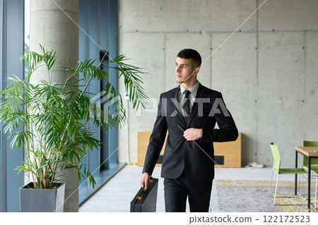 A determined businessman in a black suit confidently walks through the office, embodying professionalism and focus as he heads towards new challenges 122172523