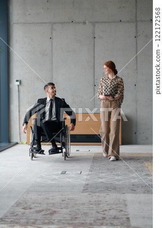 Director in a Wheelchair Navigating the Office While Discussing Business Challenges with a Colleague 122172568