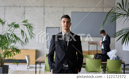 A close up portrait of a company director in a black suit, standing confidently in a modern office, exuding leadership, professionalism, and authority. 122172572