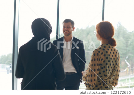 A business team engages in a lively discussion during a coffee break, exchanging challenges and sharing moments of laughter, fostering a positive and collaborative work environment 122172650