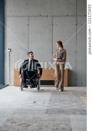 Director in a Wheelchair Navigating the Office While Discussing Business Challenges with a Colleague Director in a Wheelchair Navigating the Office While Discussing Business Challenges with a Colleague 122172655