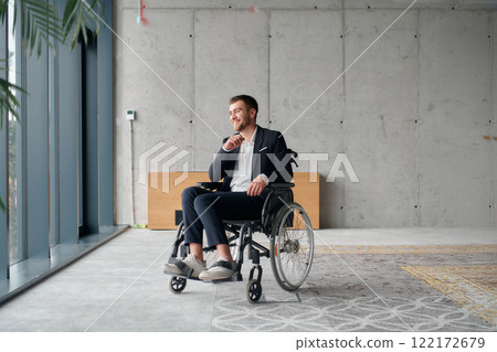 A director in a wheelchair sitting alone in an empty office, deeply reflecting on business strategies and decisions, contemplating the path forward with focused determination. 122172679