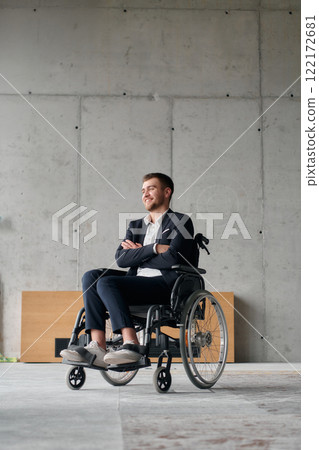 A director in a wheelchair sitting alone in an empty office, deeply reflecting on business strategies and decisions, contemplating the path forward with focused determination. 122172681