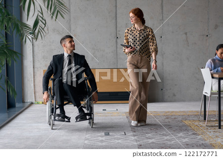 Director in a Wheelchair Engaging in a Business Discussion with a Colleague While Navigating a Modern Office 122172771