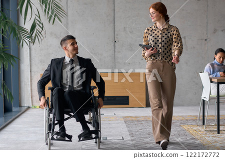 Director in a Wheelchair Engaging in a Business Discussion with a Colleague While Navigating a Modern Office Director in a Wheelchair Engaging in a Business Discussion with a Colleague While Navigating a Modern Office 122172772