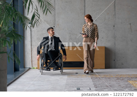 Director in a Wheelchair Engaging in a Business Discussion with a Colleague While Navigating a Modern Office 122172792