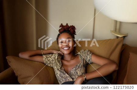 Young African woman with vitiligo smiling and relaxing on the sofa at home. Generated image 122173020