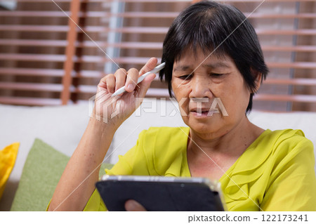 Senior asian woman sitting on sofa using digital tablet with relax in living room at home. Senior asian woman sitting on sofa using digital tablet with relax in living room at home. 122173241