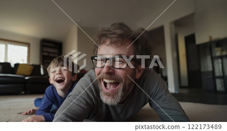Father joyfully embracing his sons at home, lying on the floor and sharing laughter. Generated image 122173489