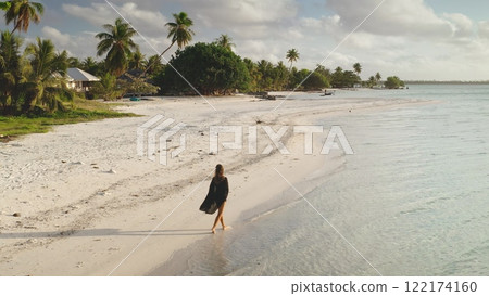 Young woman is enjoying a peaceful walk on a pristine beach in maupiti, french polynesia, as the sun sets over the horizon 122174160