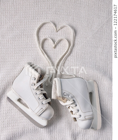 White ice skates with laces forming heart shape on knitted white fabric, symbolizing warmth, creativity, and holiday romance. White ice skates with laces forming heart shape on knitted white fabric, symbolizing warmth, creativity, and holiday romance. 122174617