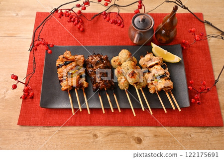 Yakitori (grilled chicken) dishes arranged on a long plate, garnished with sauce, salt, scallions, meatballs, liver, and lemon. Yakitori (grilled chicken) dishes arranged on a long plate, garnished with sauce, salt, scallions, meatballs, liver, and lemon. 122175691