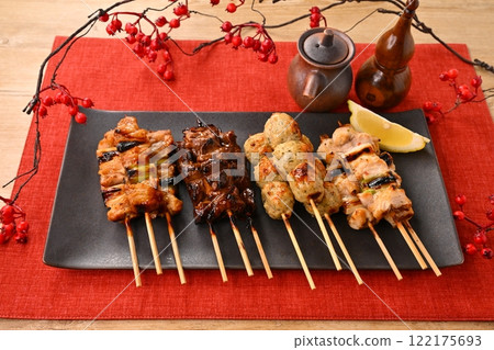Yakitori (grilled chicken) dishes arranged on a long plate, garnished with sauce, salt, scallions, meatballs, liver, and lemon. Yakitori (grilled chicken) dishes arranged on a long plate, garnished with sauce, salt, scallions, meatballs, liver, and lemon. 122175693